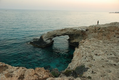 person standing on rock formation near body of water during daytime